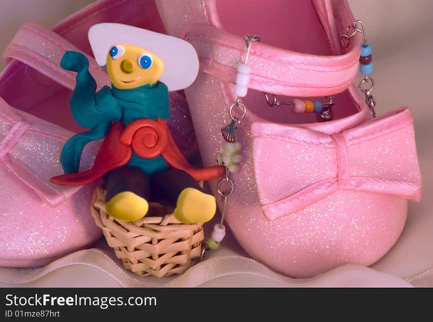 Plasticine toy and children's brilliant pink shoes,  amusing still-life. Plasticine toy and children's brilliant pink shoes,  amusing still-life