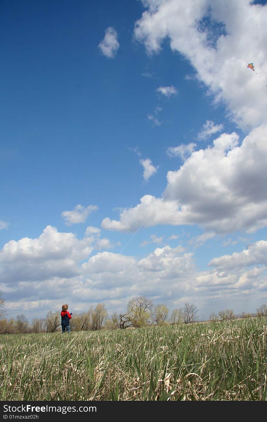 Young boy flying a kite high in the beautiful blue sky. Young boy flying a kite high in the beautiful blue sky