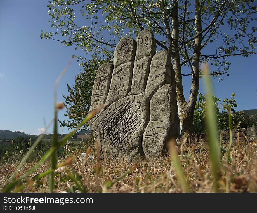 A hand of stone emerges from the field.