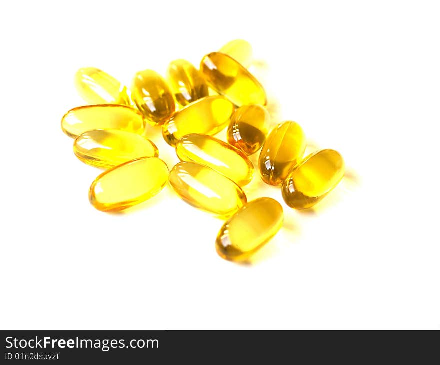 Yellow shiny pills on white background