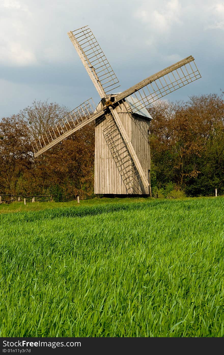 The old windmill to stand on a green field near wood