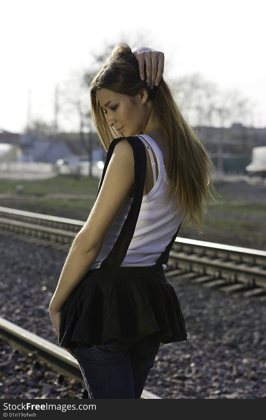 Young brunette girl standing on the railroad