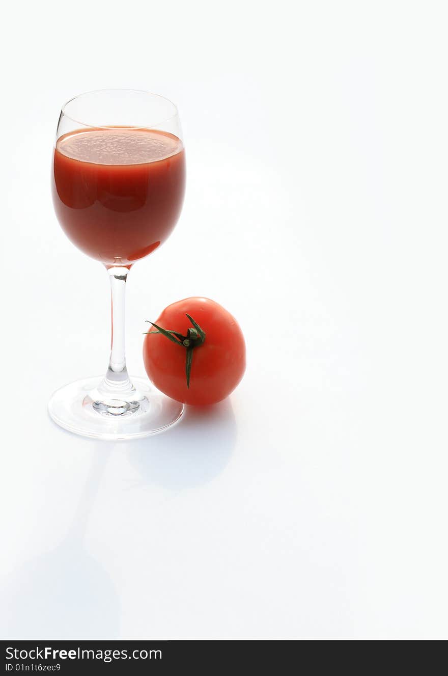 Tomato lying near goblet of tomato juice isolated on white background