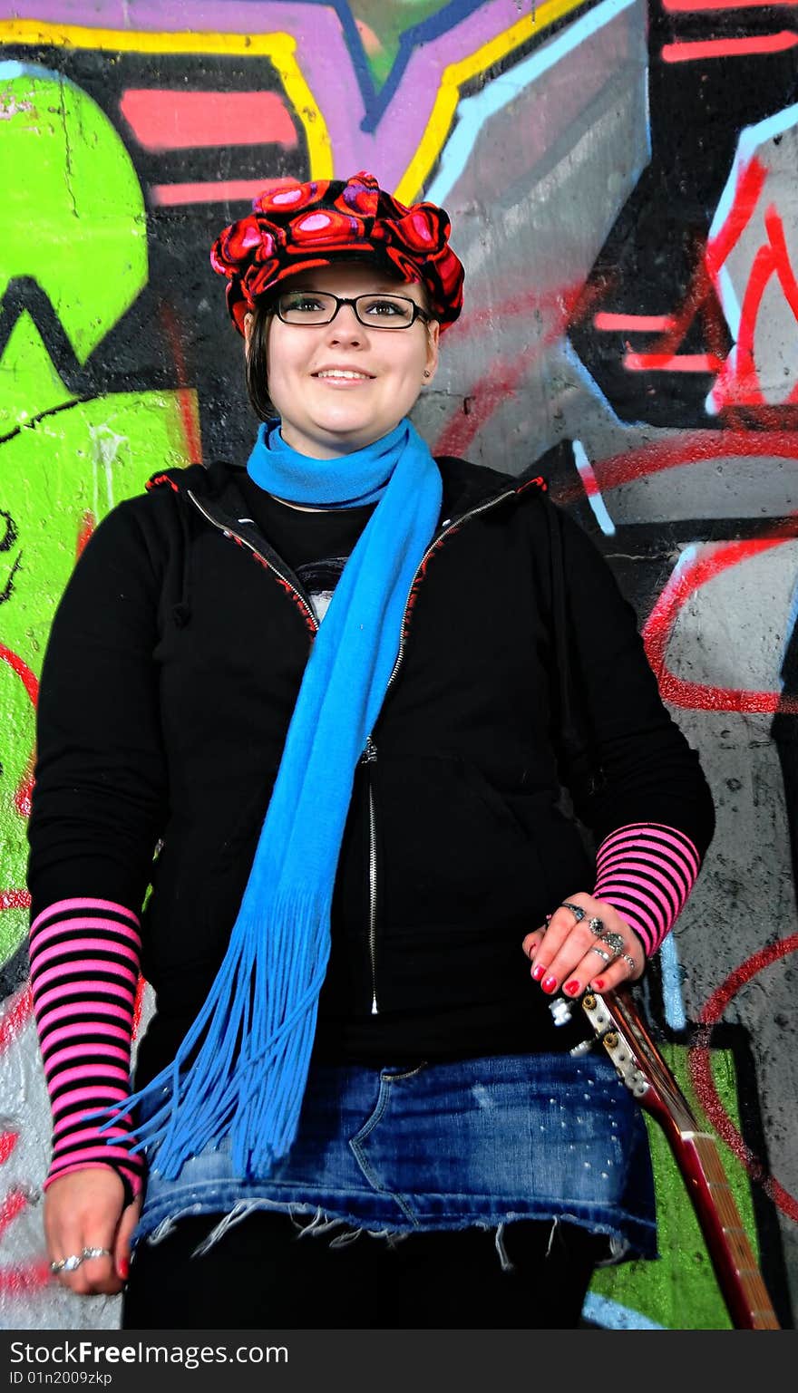 A young gothic teen holding her guitar smiling