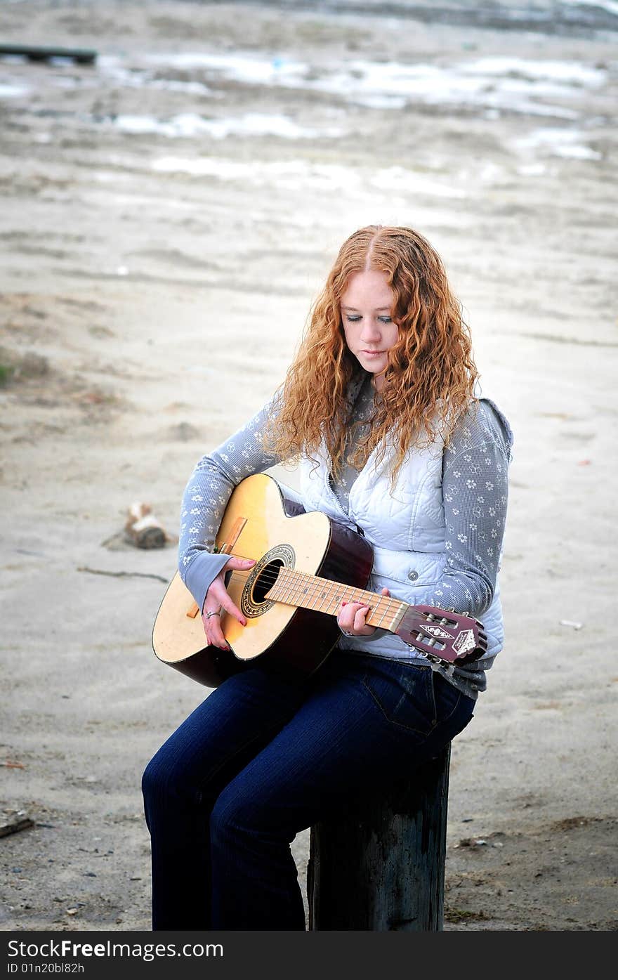 A girl with her guitar sitting on the beach. A girl with her guitar sitting on the beach