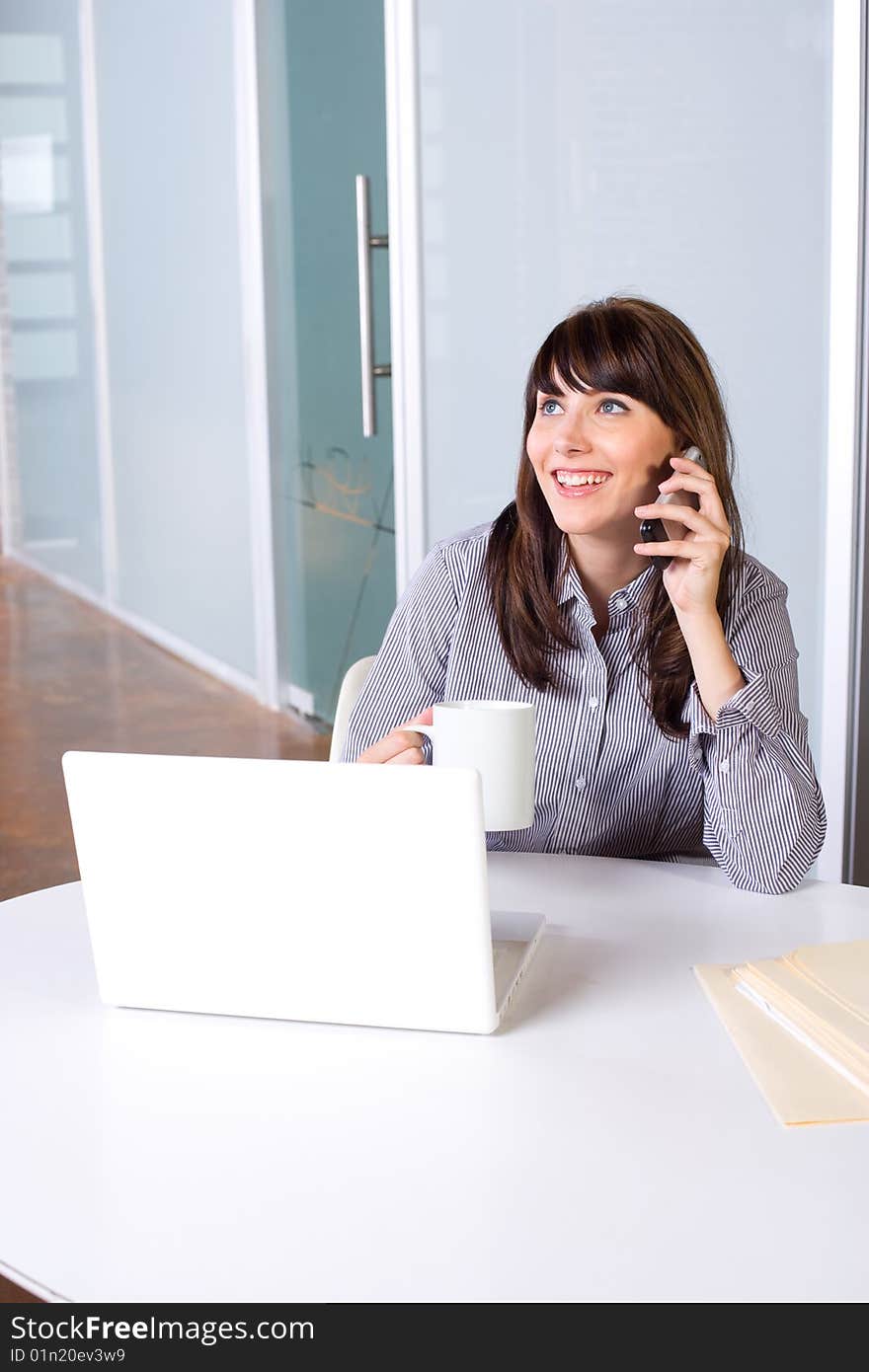 Business Woman on a cell phone and laptop in modern office