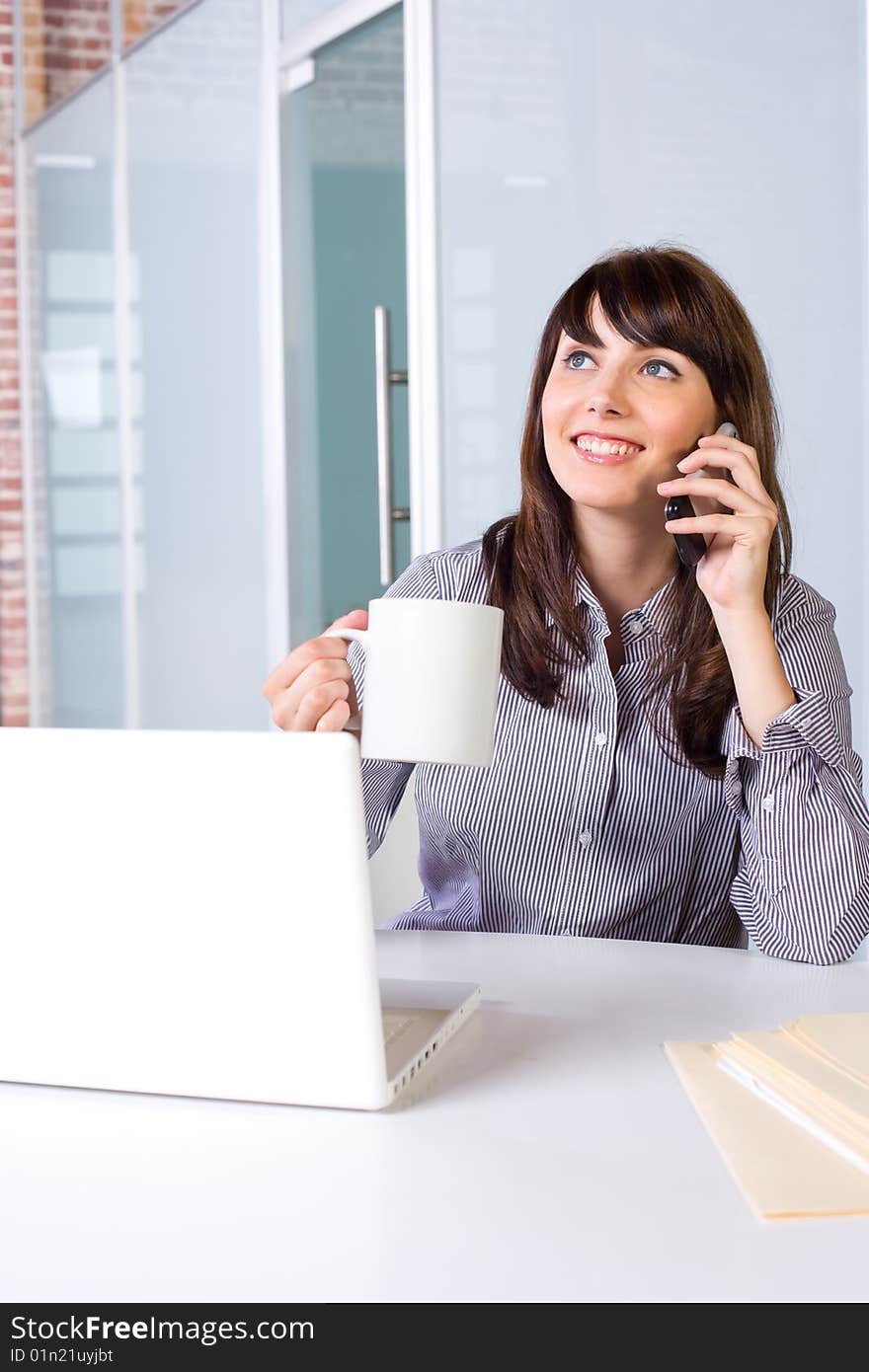 Business Woman on a cell phone and laptop in modern office