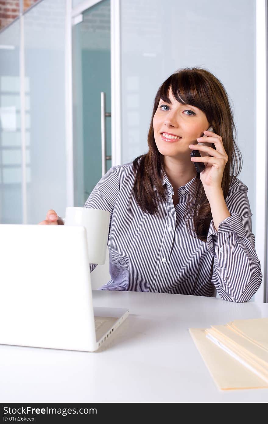 Business Woman on a cell phone and laptop in modern office