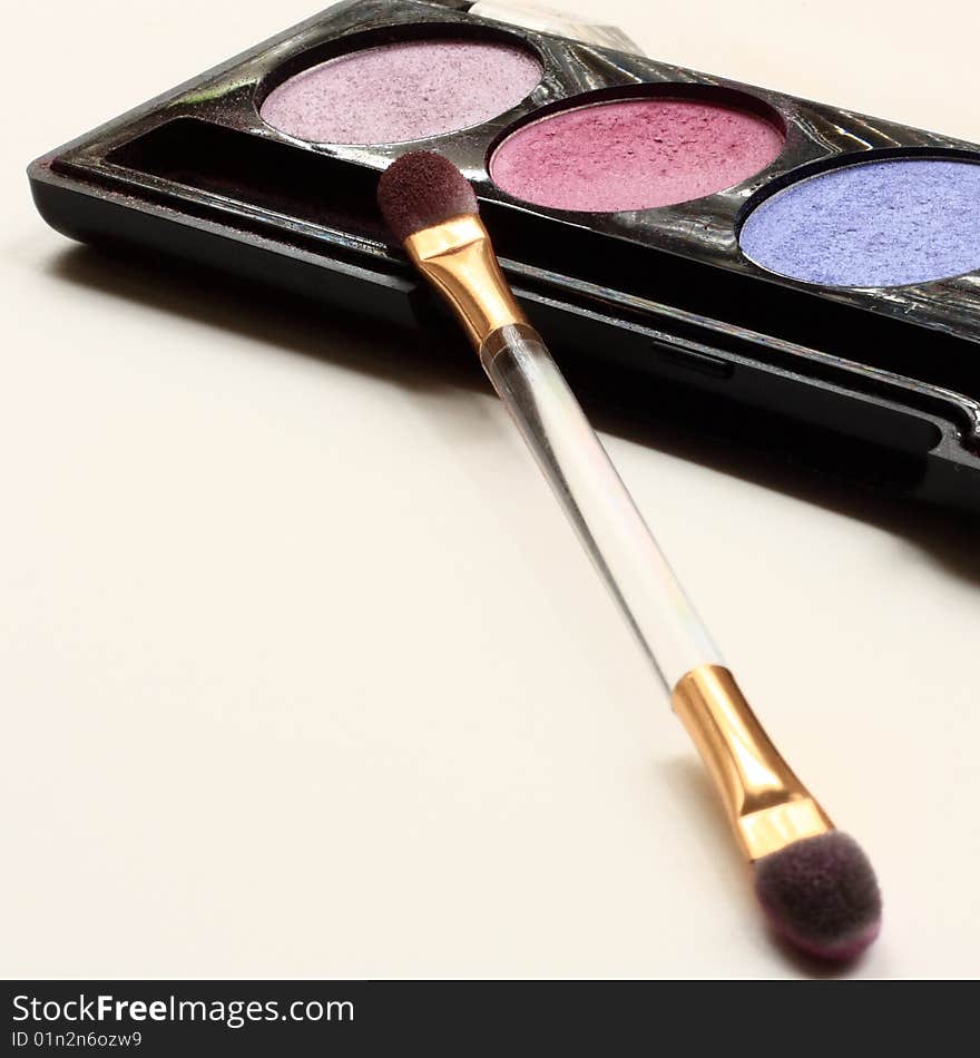 Three different eyeshadow colors and a brush