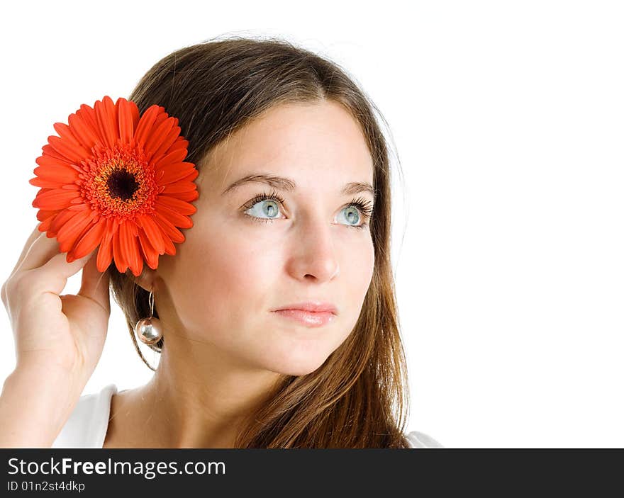 A smiling beautiful young woman in a white dress with a bright red flower near her face. A smiling beautiful young woman in a white dress with a bright red flower near her face