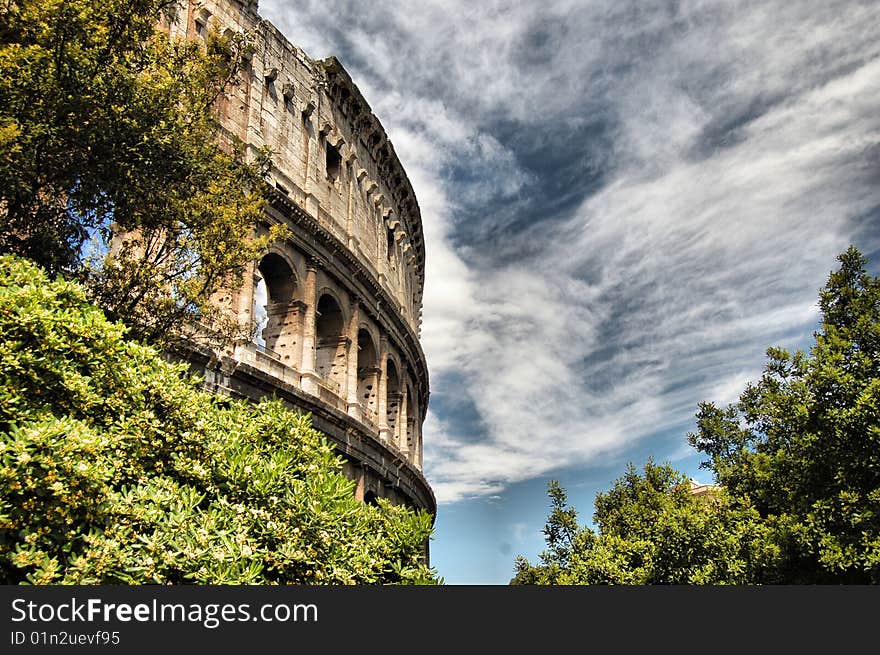 A foreshortening, HDR modified, of the roman colosseum with clouds and trees. A foreshortening, HDR modified, of the roman colosseum with clouds and trees.