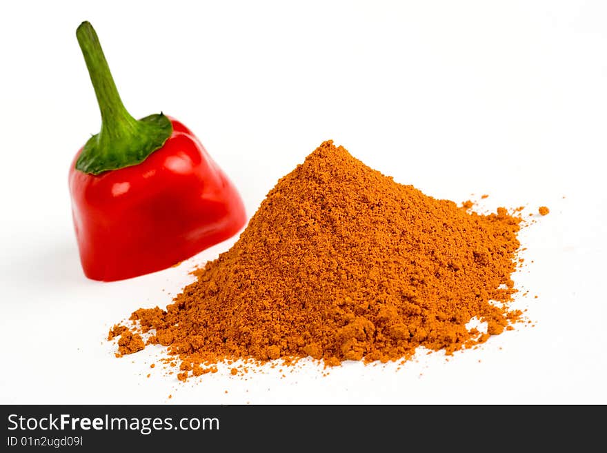 A  piece of red hot pepper near  ground pepper on a white background. A  piece of red hot pepper near  ground pepper on a white background