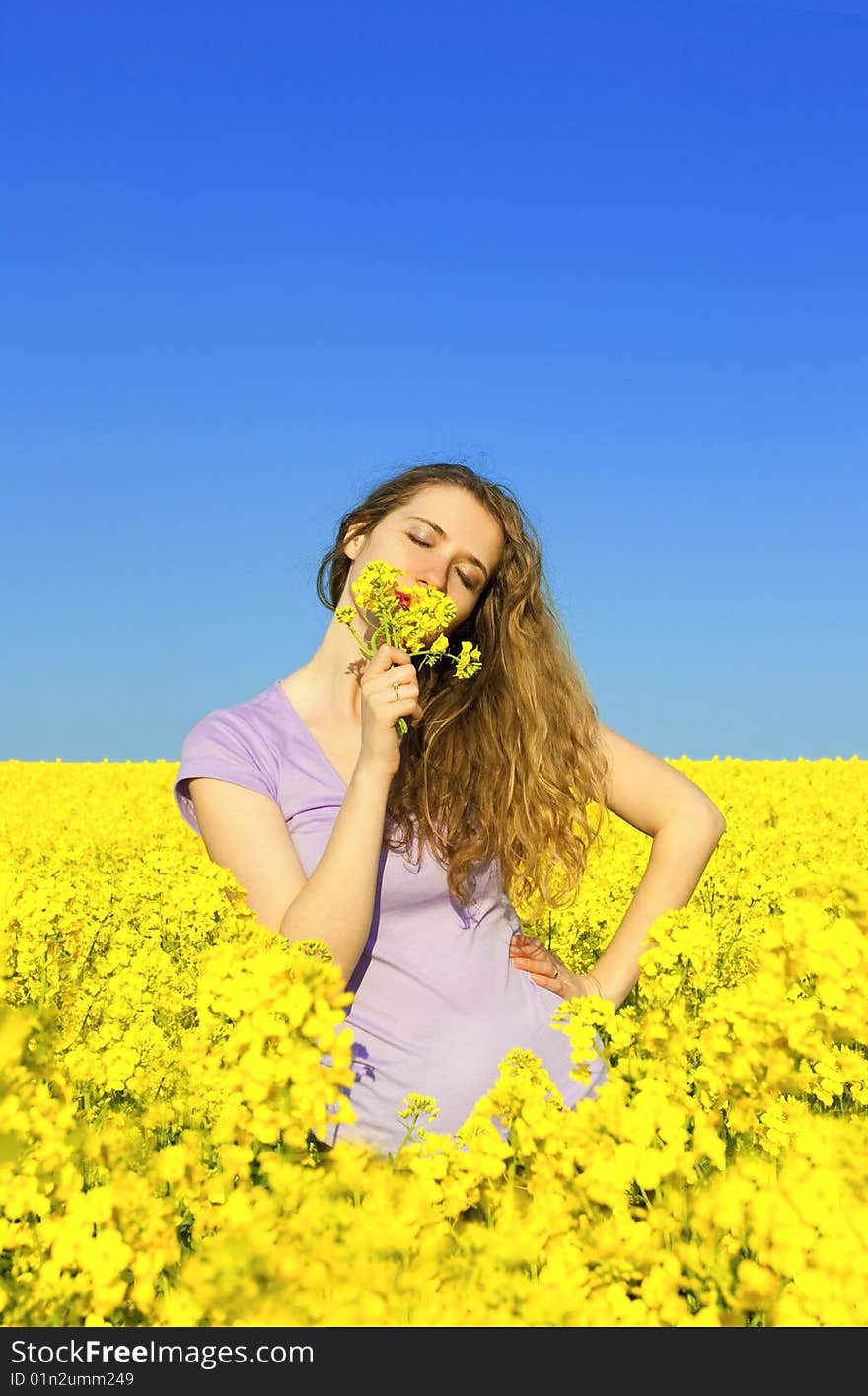 Woman in rape(canola) field smelling flowers. Woman in rape(canola) field smelling flowers