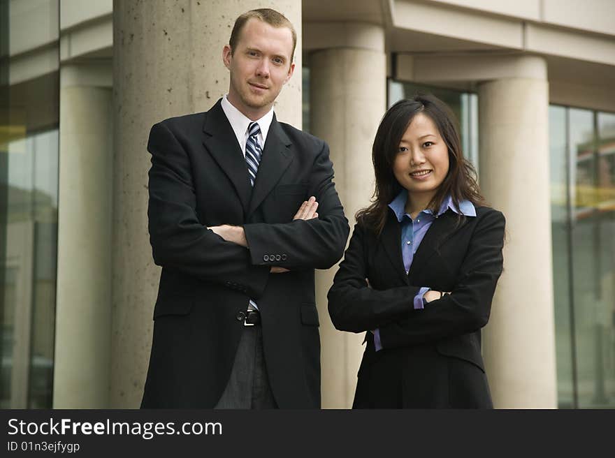 Confident businessman and businesswoman posing n front of an office building. Confident businessman and businesswoman posing n front of an office building.