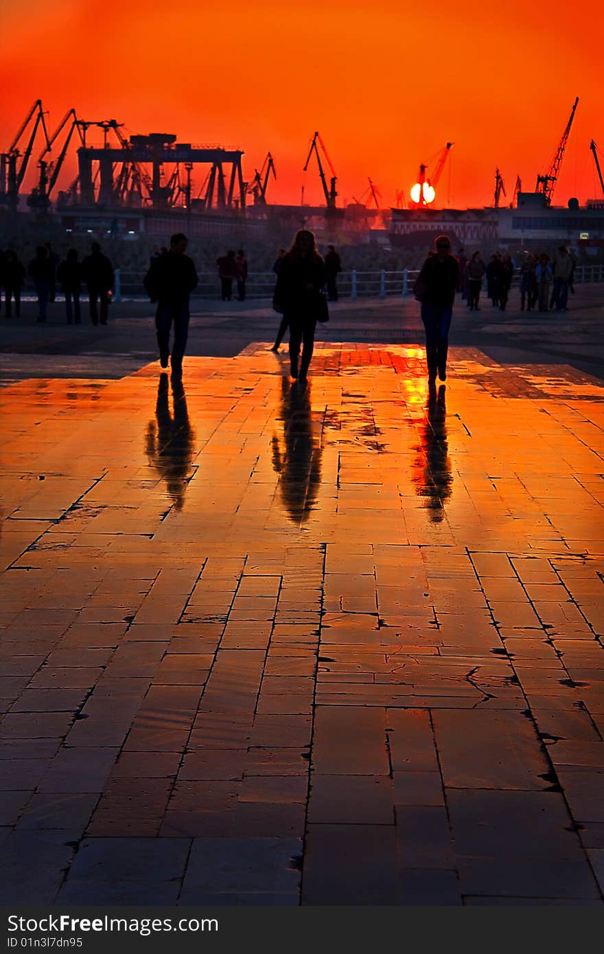 Three people walking near the harbor