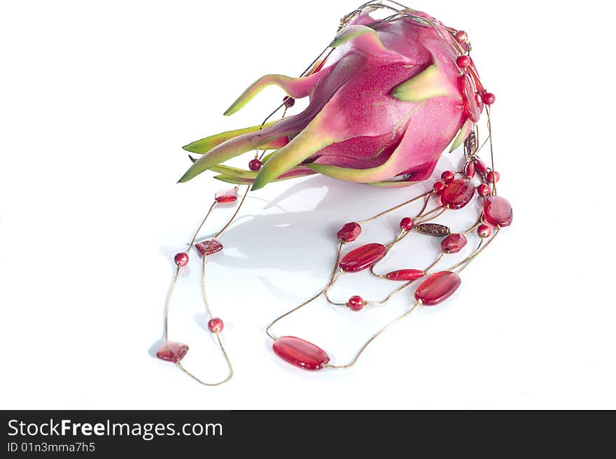 Red necklace and dragon fruit on white surface backgroun