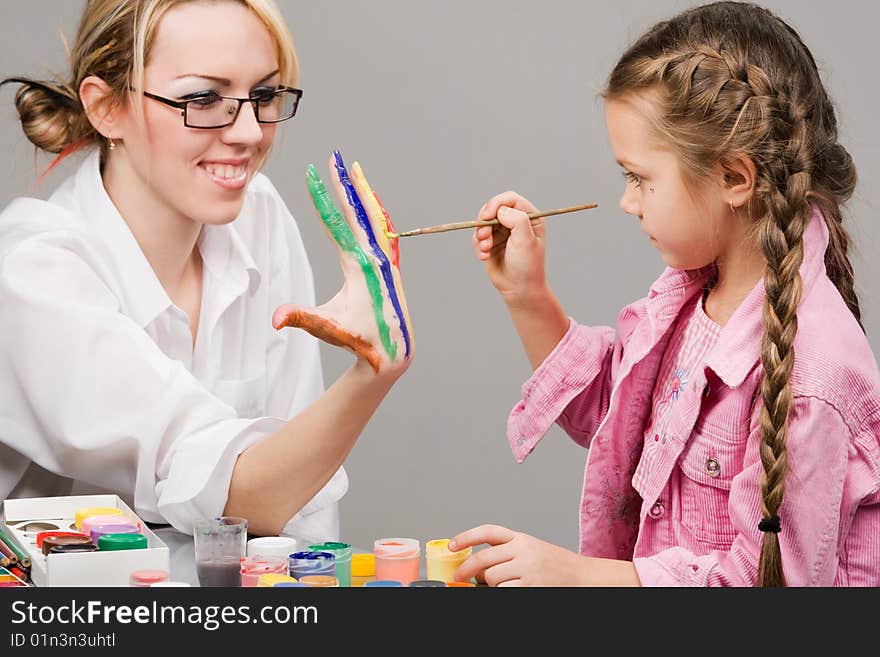 Little girl playing with mom, painting her fingers. Little girl playing with mom, painting her fingers