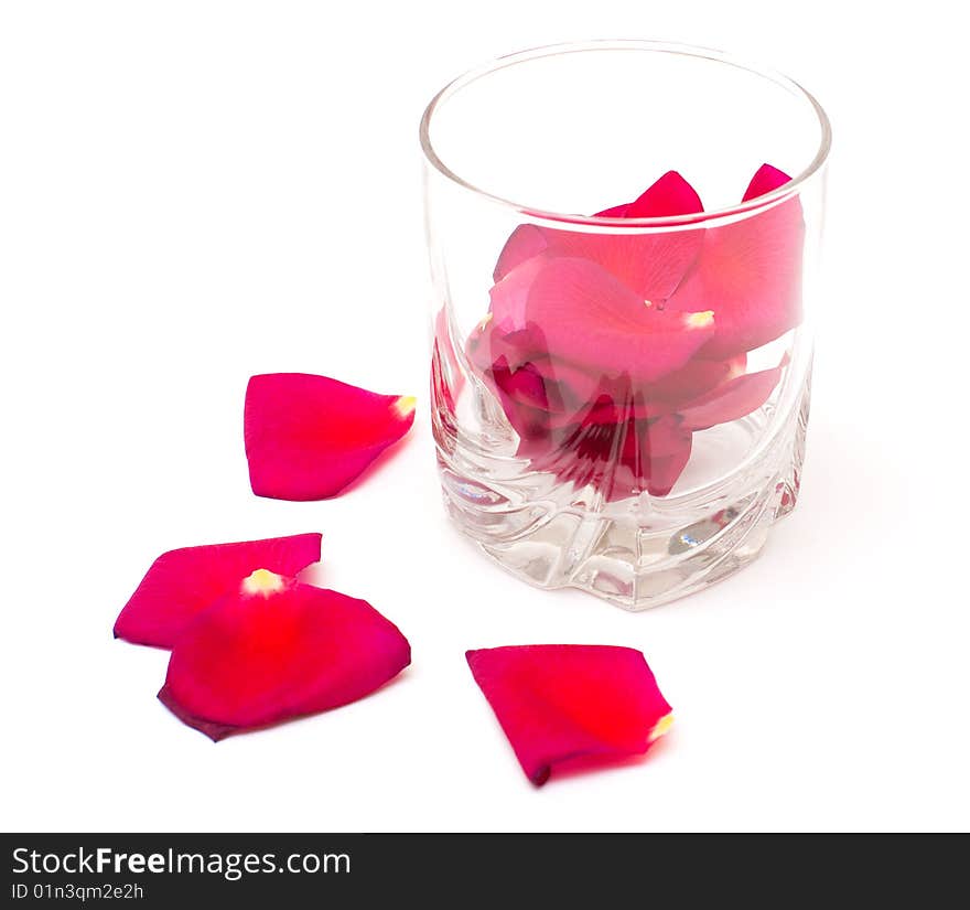 Glass and petals of rose isolated