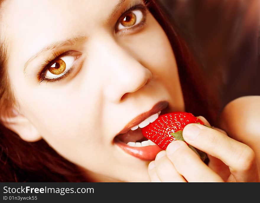 Young sexy woman, strawberry between her lips, looking at camera