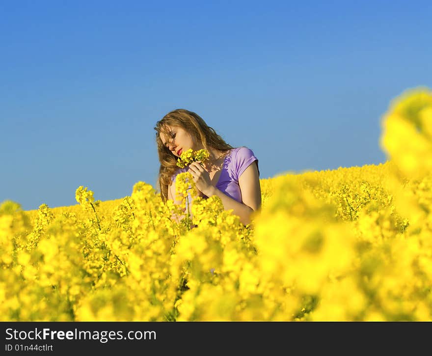 Woman in rape(canola) field smelling flowers. Woman in rape(canola) field smelling flowers