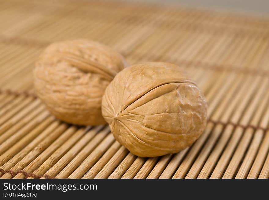 Two walnuts on bamboo mat.