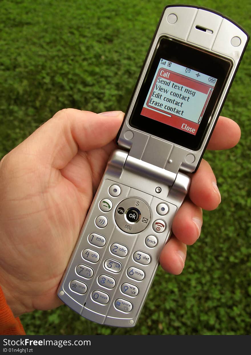 Photo of cell phone being used outdoors with lush spring time grass as a backdrop. Photo of cell phone being used outdoors with lush spring time grass as a backdrop.