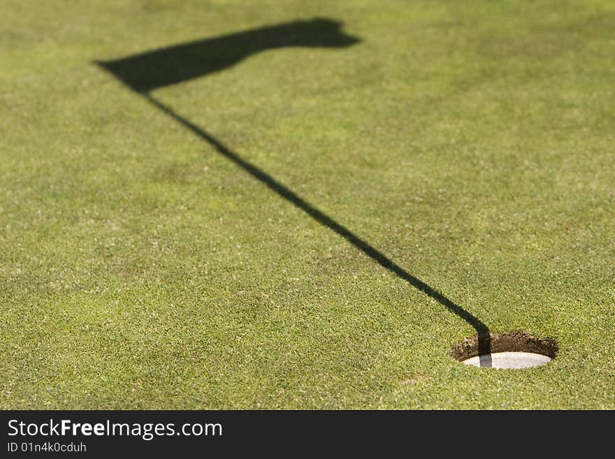 Golf field showing the hole and the flag shadow