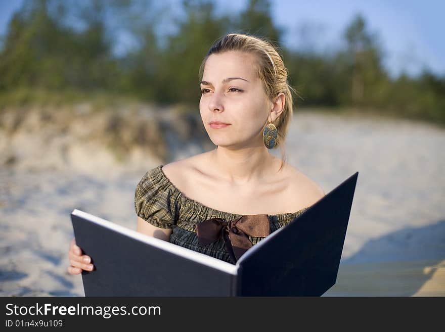 Girl with book on the beach in light of sunset. Girl with book on the beach in light of sunset