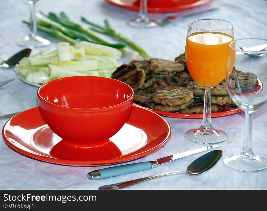 Red plates and orange juice served on table in kitchen. Red plates and orange juice served on table in kitchen