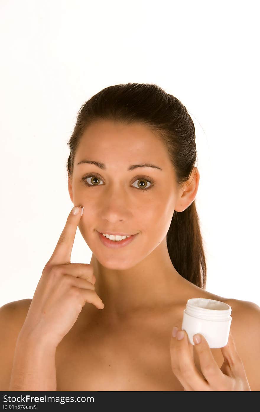 Young brunette applying cream on her face