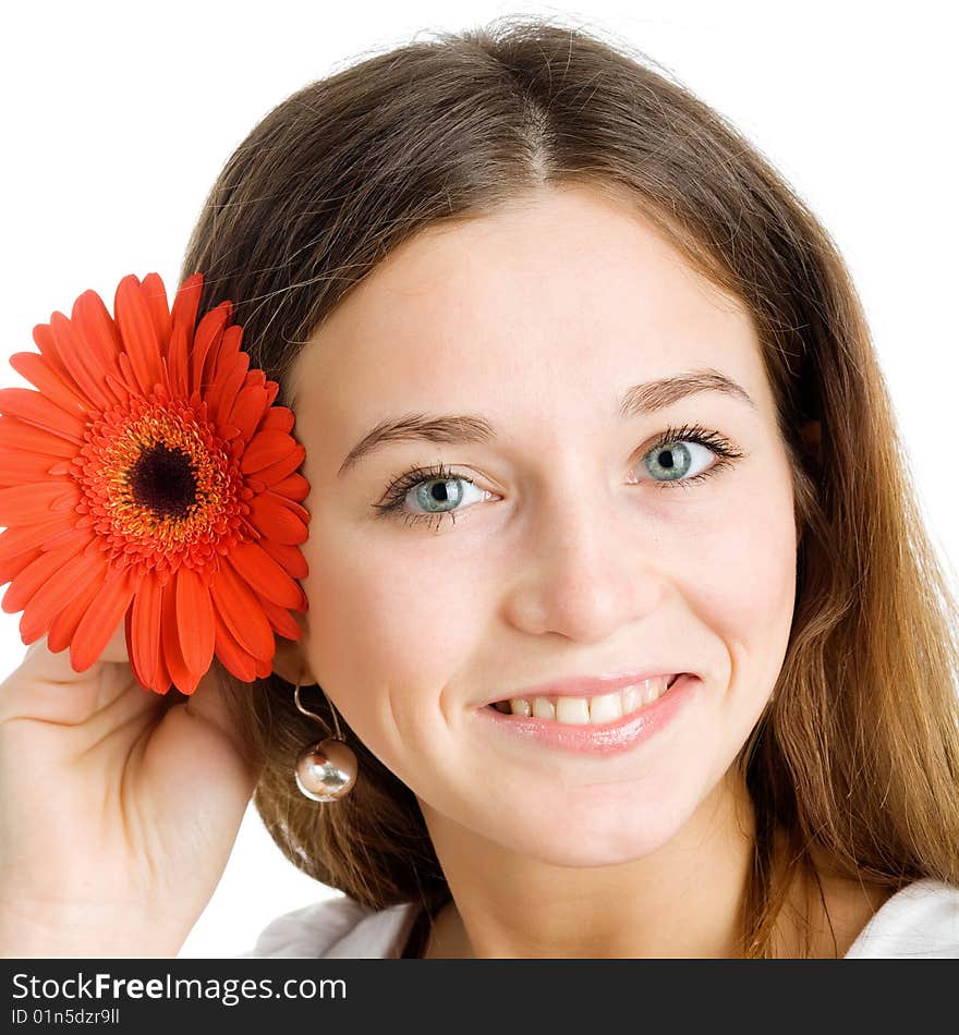 A smiling beautiful young woman in a white dress with a bright red flower near her face. A smiling beautiful young woman in a white dress with a bright red flower near her face