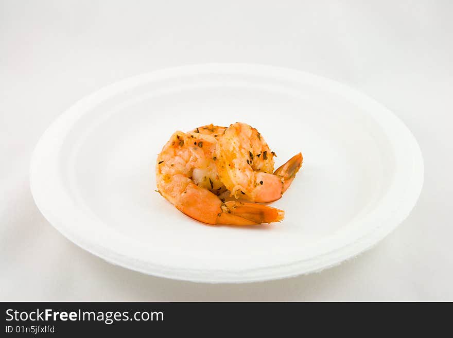 Two spicy pink prawns on a white plate with a white background. Two spicy pink prawns on a white plate with a white background