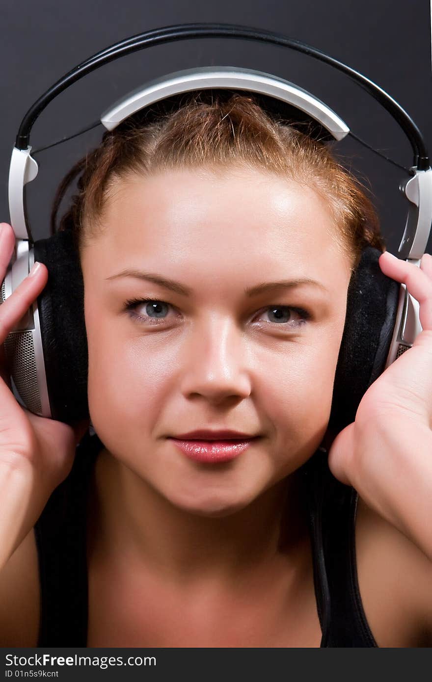 Beautiful girl in ear-phones on a dark background. Beautiful girl in ear-phones on a dark background