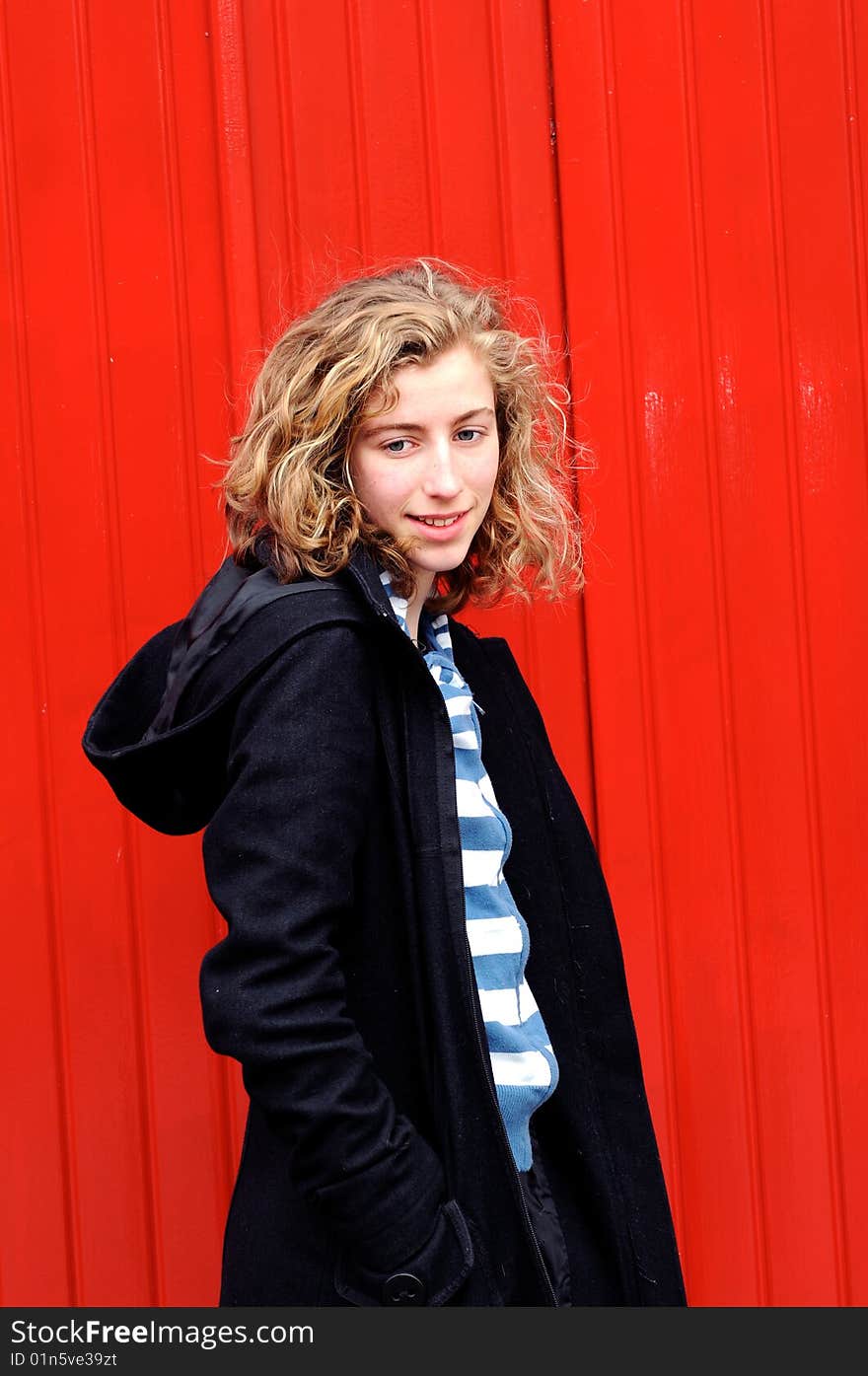 Portrait of pretty teenage girl against red wall