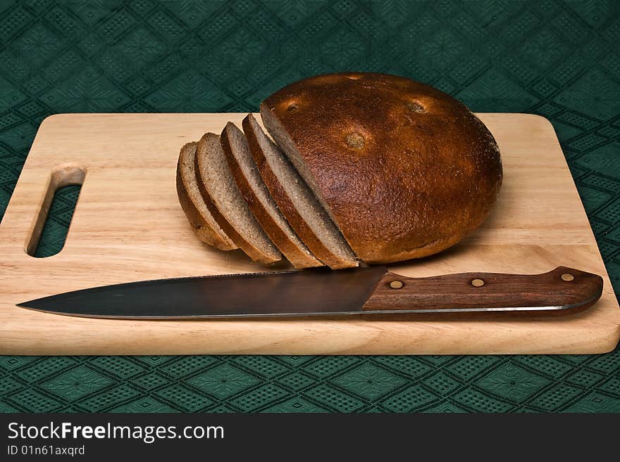 Brown bread and knife on a chopping board. Brown bread and knife on a chopping board