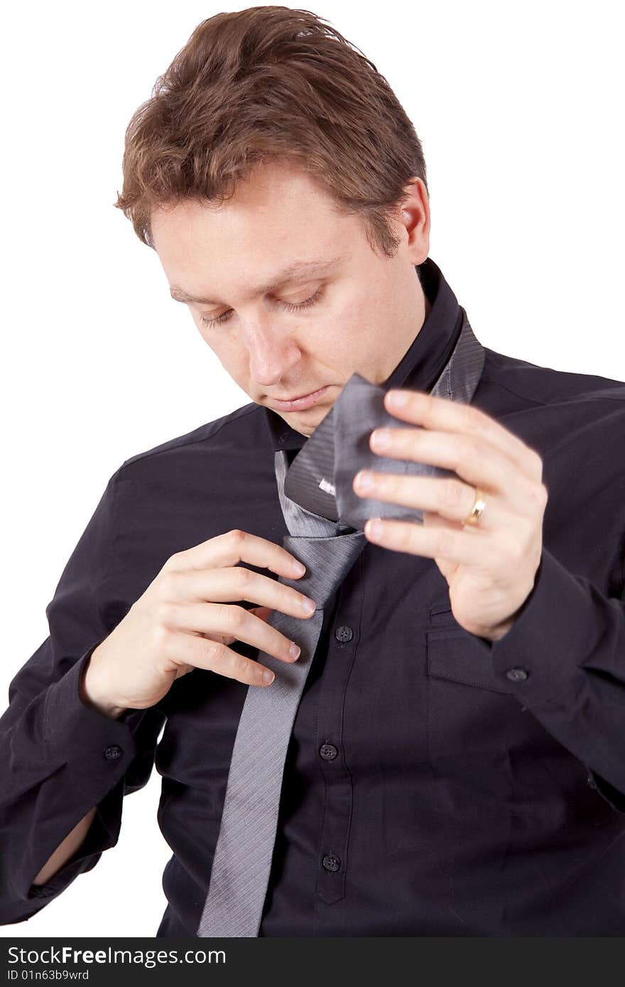 A young businessman is tying a tie