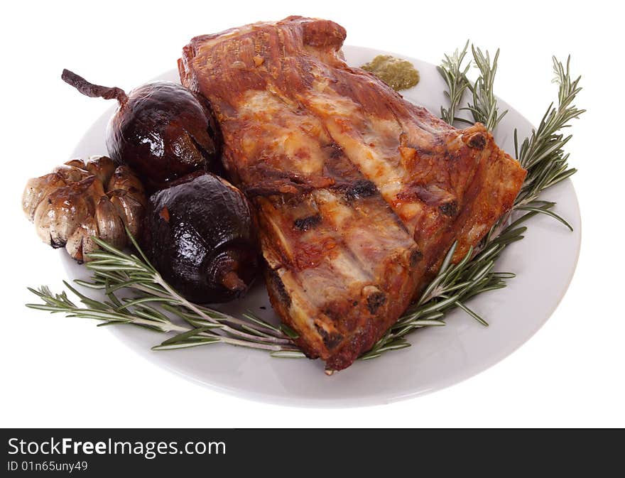 Grilled pork ribs with onions, garlic and rosemary on a plate, isolated on white background