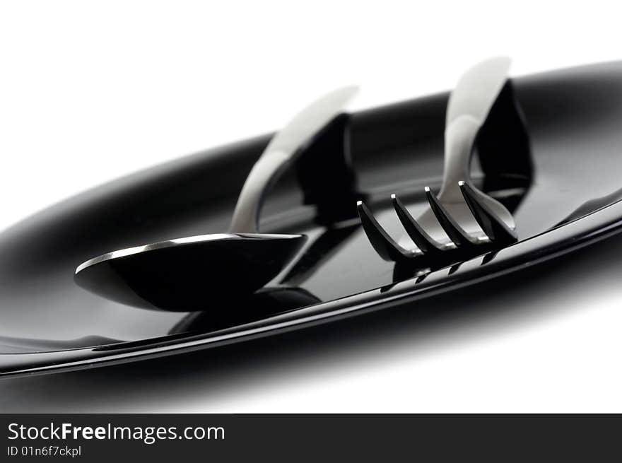 Fork and spoon on black plate. Fork and spoon on black plate