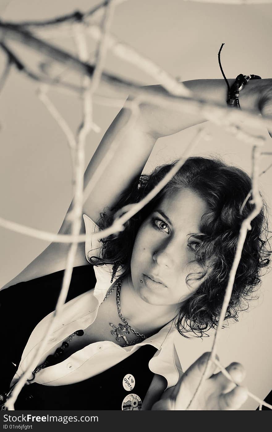 Portrait of a young beautiful girl in black and white with branches in the foreground. Portrait of a young beautiful girl in black and white with branches in the foreground