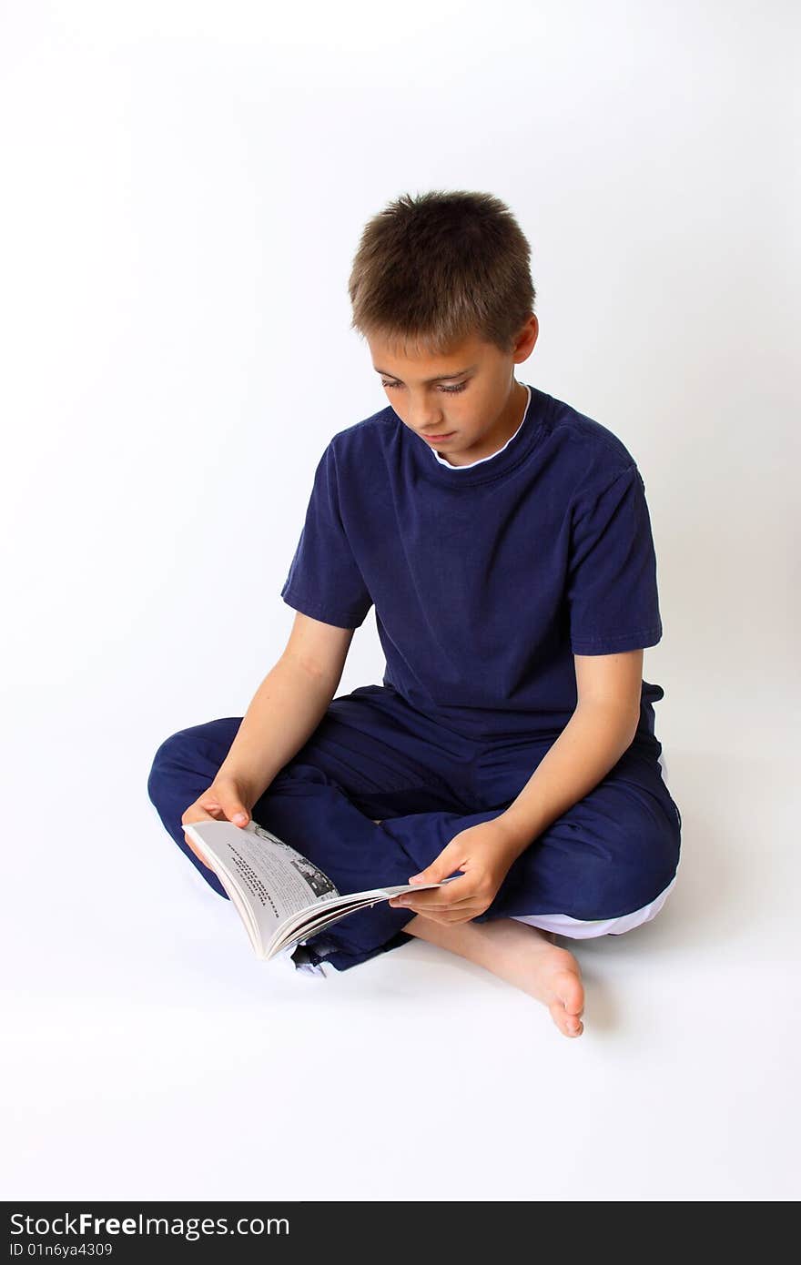 Boy dressed in blue reading book on white backdrop. Boy dressed in blue reading book on white backdrop