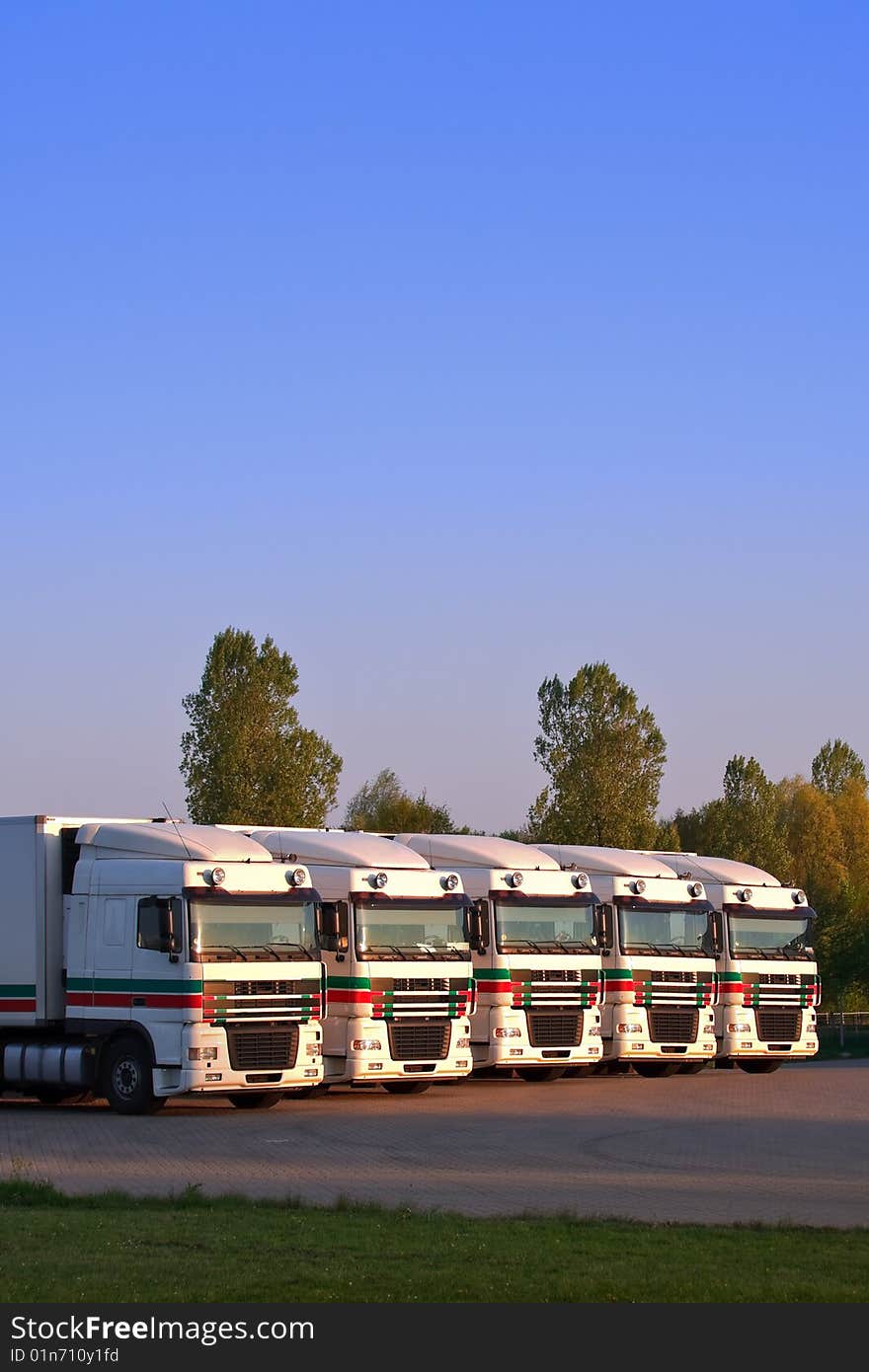 Five trucks in a row with trees and blue sky