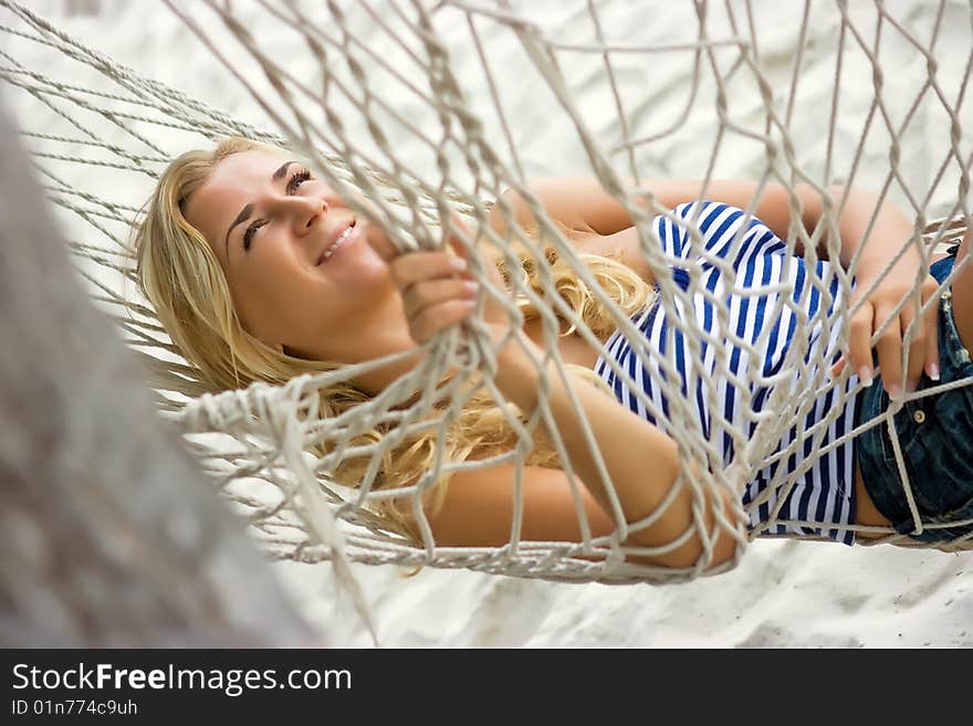 Blonde girl relaxing in hammock on the sandy beach