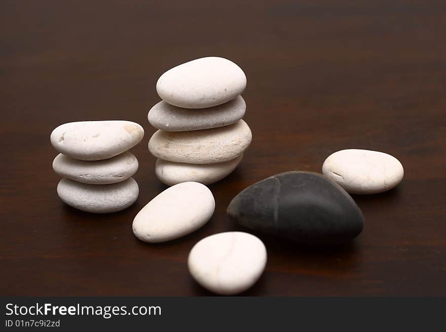 A collection of white and black pebbles arranged on a wood grain. A collection of white and black pebbles arranged on a wood grain.