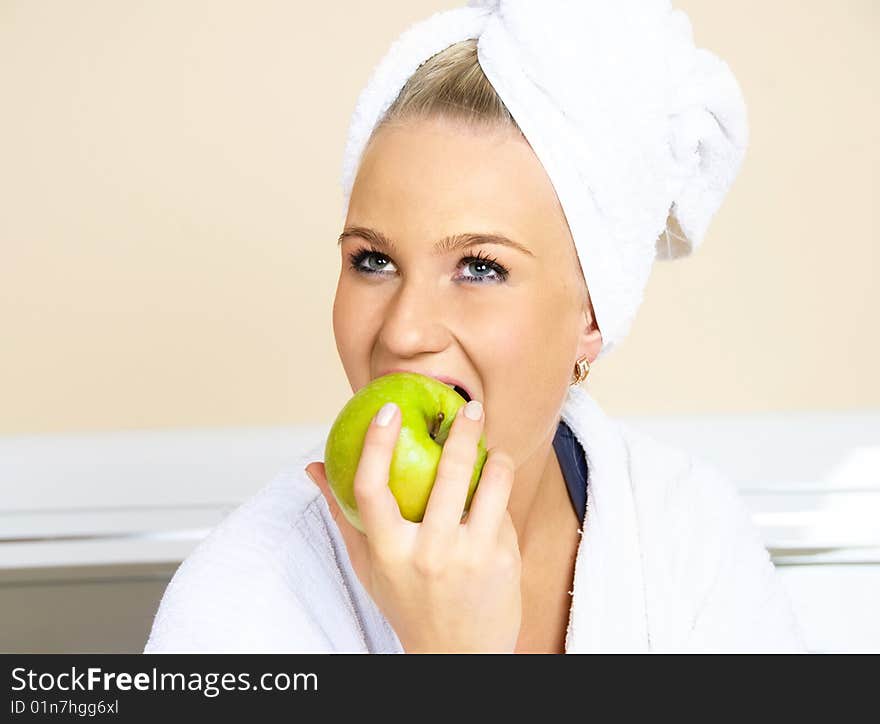 Pretty young woman sitting on the bed at home and eating an apple. Pretty young woman sitting on the bed at home and eating an apple