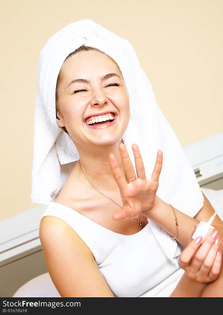 Pretty laughing young woman at home applying nail polish. Pretty laughing young woman at home applying nail polish