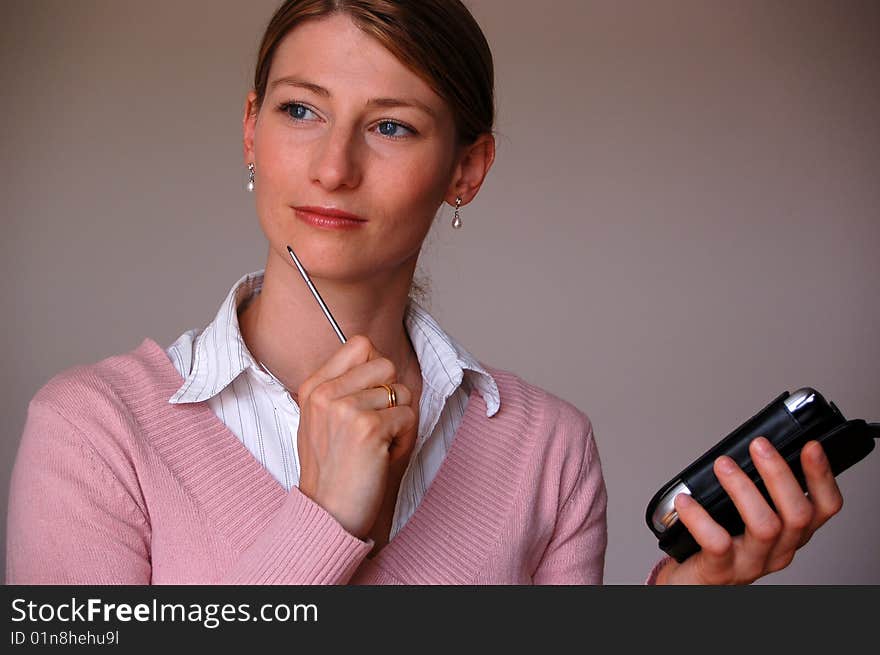 Attractive thoughtful woman holding a pda. Attractive thoughtful woman holding a pda