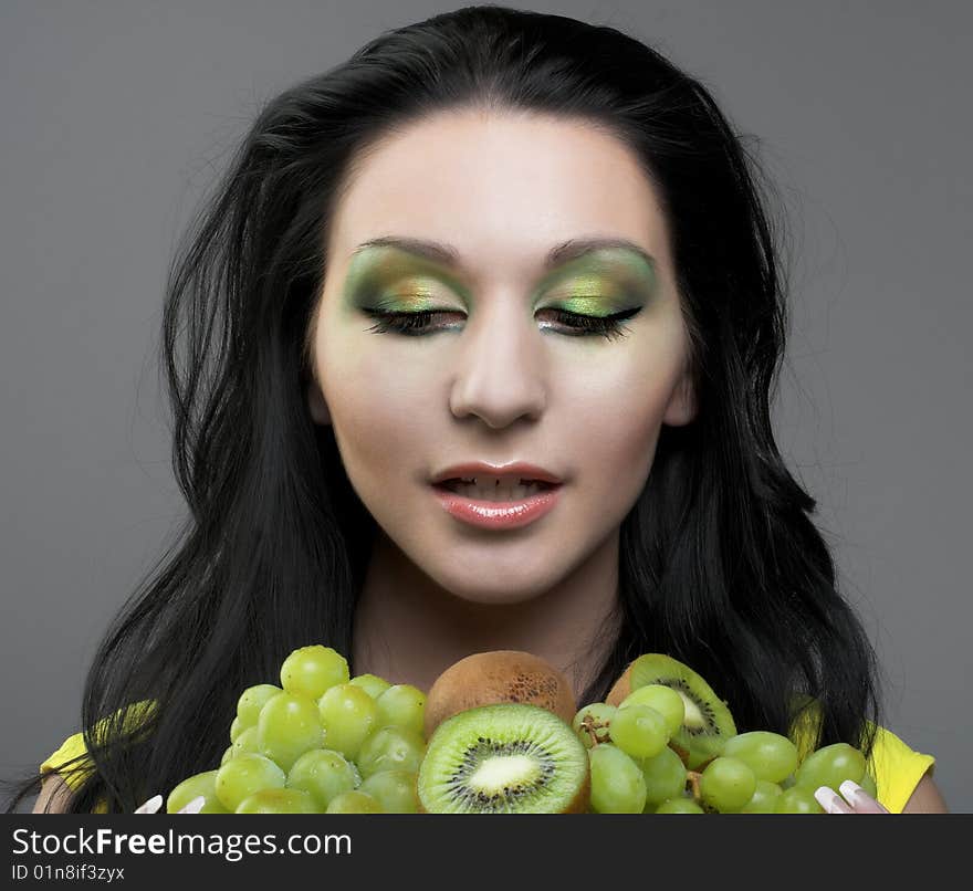 Portrait of young woman witn kiwi and green grapes. Portrait of young woman witn kiwi and green grapes