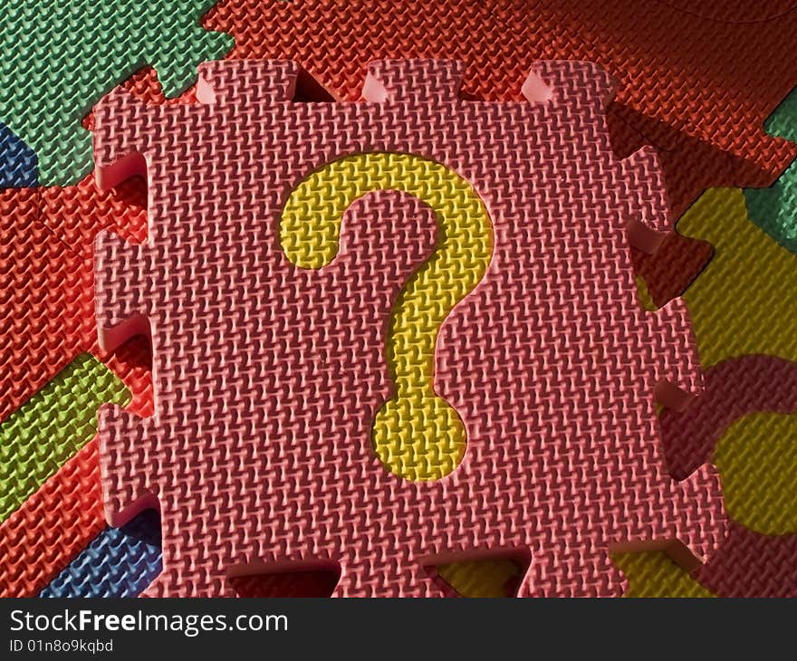 Jigsaw, pink puzzle with a bright yellow question mark, isolated on other colorful sponge pieces of the puzzle. Jigsaw, pink puzzle with a bright yellow question mark, isolated on other colorful sponge pieces of the puzzle