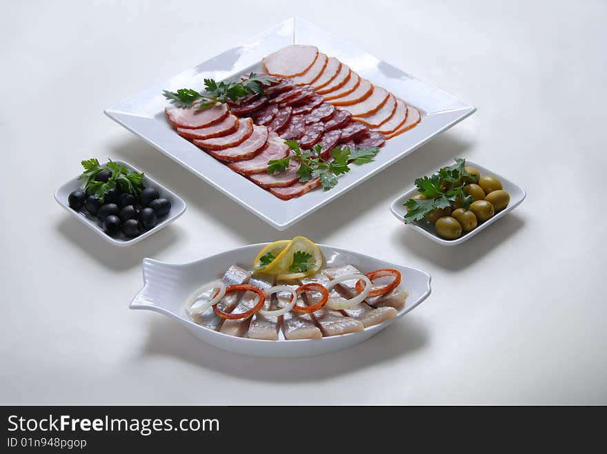 On a plate lined herring, olives and smoked. On a plate lined herring, olives and smoked