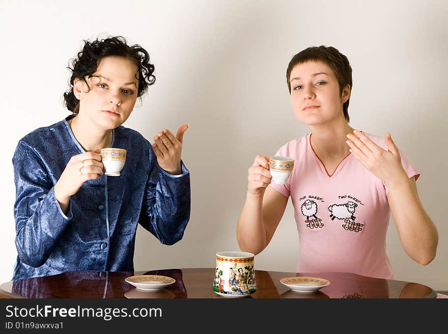 Two young women sitting at a table and drinking a tea. Two young women sitting at a table and drinking a tea